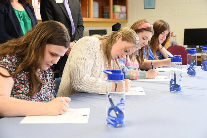 Four Russell County High School seniors sign their commitment to RCHS’s apprenticeship program with Lindsey Wilson College. The students will work under a mentor teacher while simultaneously taking dual credit courses with LWC’s education program, complete student teaching hours and fast-track their way to earning a degree. From left: Leah White, Emma Wilson, Anna Gosser, Saturn Taryn Walsh.