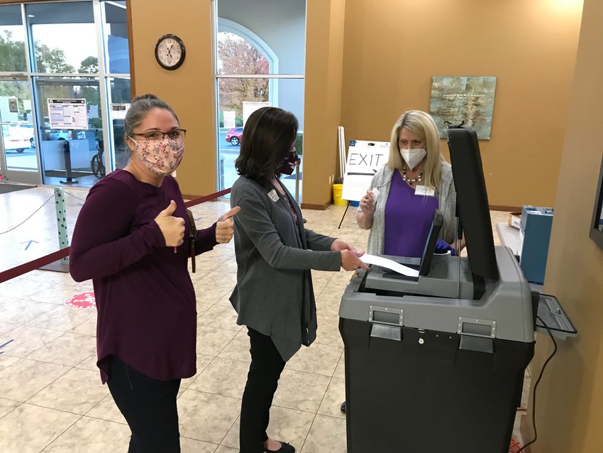 Sadie Fisher (far left) shoots two thumbs up towards the camera as Baxter County Clerk Canda Reese (middle) and election worker Lyn Keaster feed Fisher's ballot into the tabulator at the First United Methodist Church early voting site on Monday evening. Fisher was the final citizen to early vote at the site, completing her ballot shortly after 5 p.m.