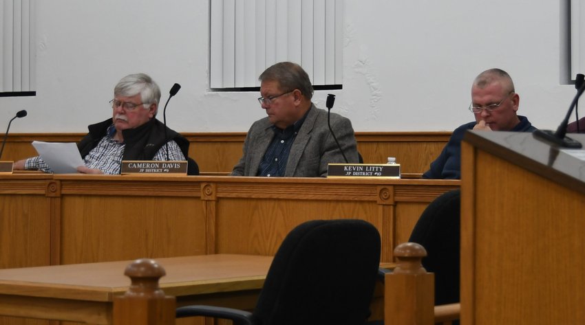 Baxter County Justices of the Peace (from left) Roger Steele, Cameron Davis and Kevin Litty review an ordinance finalizing the county's 2021 millage rates Tuesday night at the Quorum Court's November meeting.