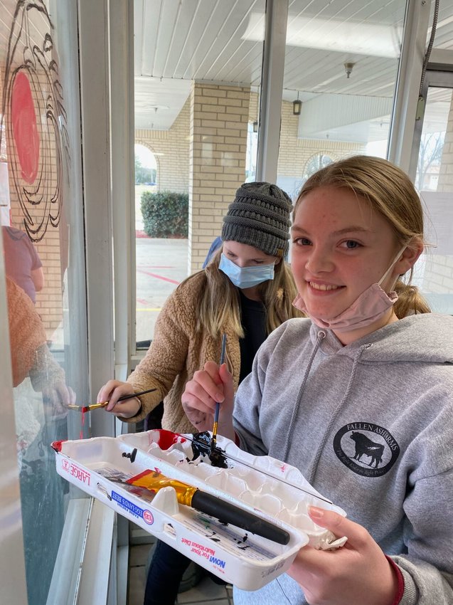 Flippin High School Art Club members who recently &quot;painted the town&quot; with Christmas cheer. Shown are (front) Adrianne Benedict and Elle Mitchell as they paint holiday cheer on local business windows.