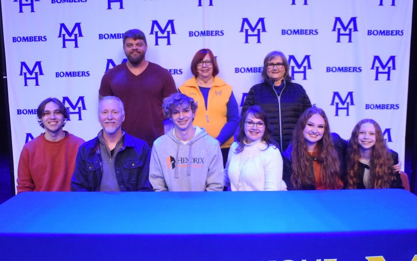Mountain Home's Aidan Wilson (front row, third from left), pictured with family and coaches, signed Wednesday to swim at Hendrix University.