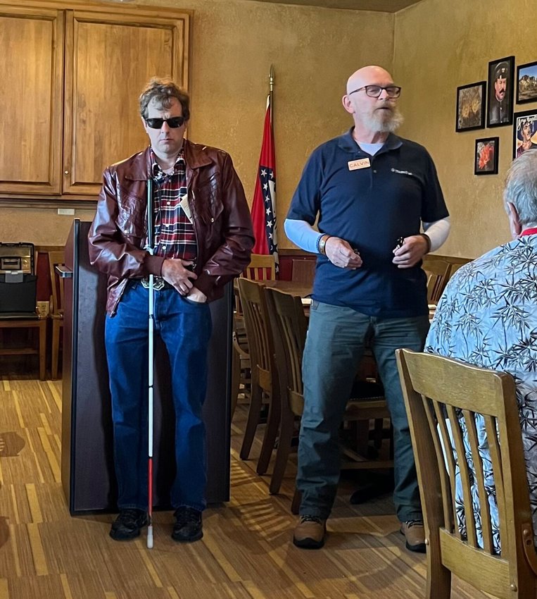 During the Mountain Home Lions Club May 25 meeting, Lion member Tim Herold, who is visually impaired, assisted Calvin Churchwell with NanoPac, Inc. Churchwell brought a OrCam MyEye Pro &ldquo;reading device,&rdquo; one of more than 200 the company sells. The unobtrusive, battery-powered unit contains a small camera and powerful onboard processing power to provide instant and discreet help with reading, face recognition, color, product identification and more &mdash;&nbsp;and will repeat what it &ldquo;sees&rdquo; in a computerized voice for the wearer.   Helen Mansfield/The Baxter Bulletin