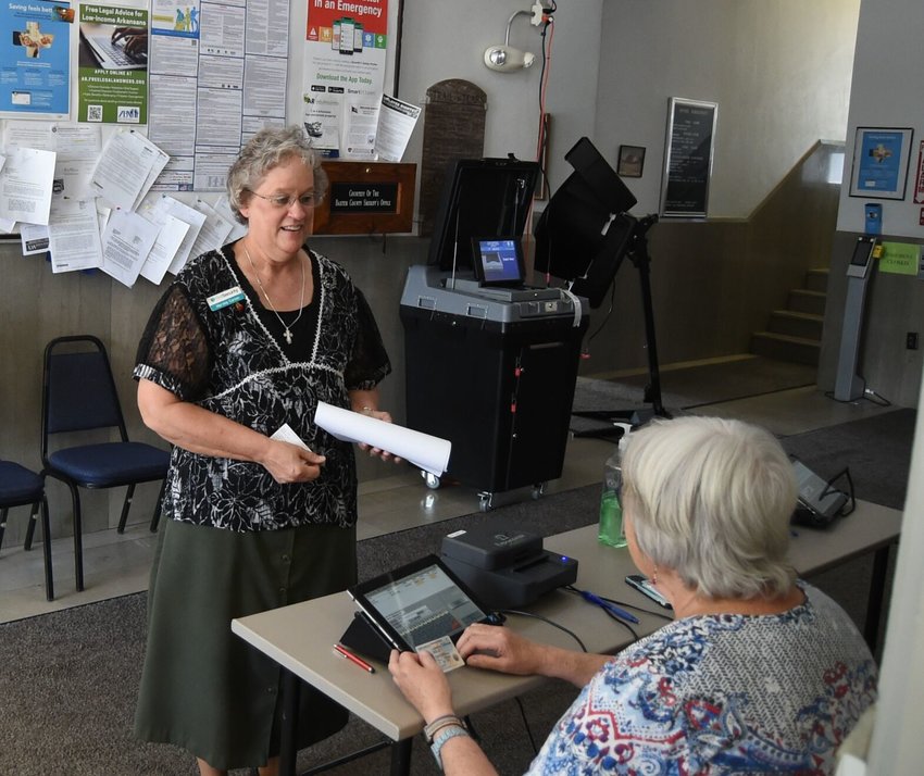 Marvina Carson of Gassville (standing) checks in Thursday at the Baxter County Courthouse to cast her ballot in the county's runoff elections. Seated is poll worker Sue McLarry.&nbsp;Election day for the area's runoff races is Tuesday, with early voting closing Monday afternoon.   Scott Liles/The Baxter Bulletin