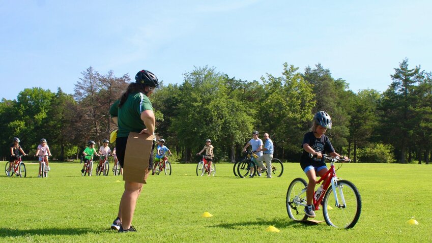 Mountain Home Parks and Recreation (MHPR) Recreation Program Coordinator Megan Engeler (left) observes a child completing a bicycle drill during the &quot;Demo Day&quot; for a brand-new children's biking program launching in Mountain Home later this month.   Ethan Graniss/Special to The Bulletin