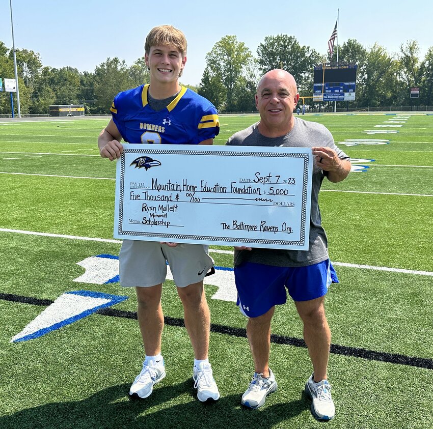 Mountain Home head football coach Steve Ary (right) and senior quarterback Cade Yates accept a $5,000 donation to the Mountain Home Education Foundation from the Baltimore Ravens in memory of Ryan Mallett. Mallett, who played for the Ravens from 2015 to 2017 and coached two seasons of Bomber football in 2020 and 2021, passed away June 27. A scholarship through the MHEF was set up in his memory with the purpose of helping football players further their post-secondary academic endeavors. Those interested in contributing to the Ryan Mallett Memorial Scholarship fund may visit mountainhomeeducationfoundation.com/donate for more information on how to donate.