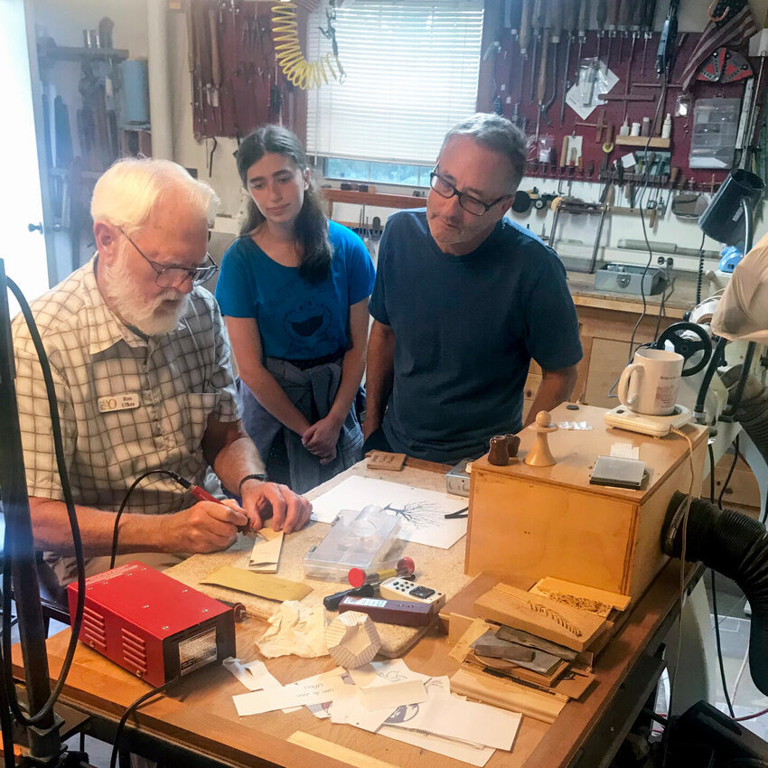 Art Odyssey artist Ron Ufkes (left) demonstrates woodworking to onlookers&nbsp; during the past Art Odyssey tour.   Submitted Photo