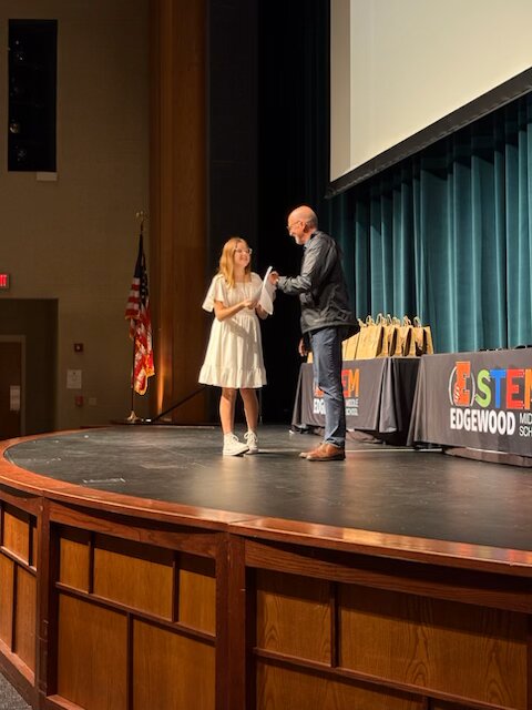 OrthoWorx’s Vice President of Operations & Engagement, Allyn Decker, hands a Peace Builder Award to Audrey Green from Edgewood Middle School.
