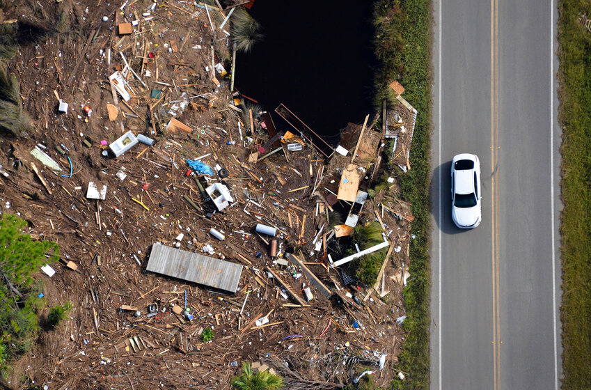 A car is seen driving alongside storm debris on south-east Highway 357 in Old Town, Fla., on Thursday, Aug 31, 2023, following Hurricane Idalia’s landfall in Keaton Beach, Fla., Wednesday morning. (Caleb Ross/WUFT News)