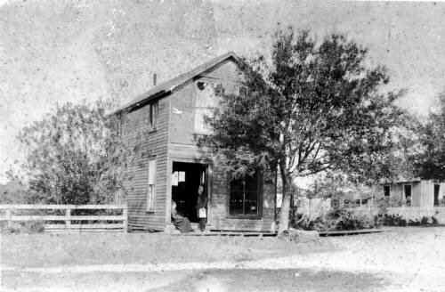 The Sarasota Times building on Main Street.  C.V.S. Wilson, and his wife, Rose sit in the doorway.