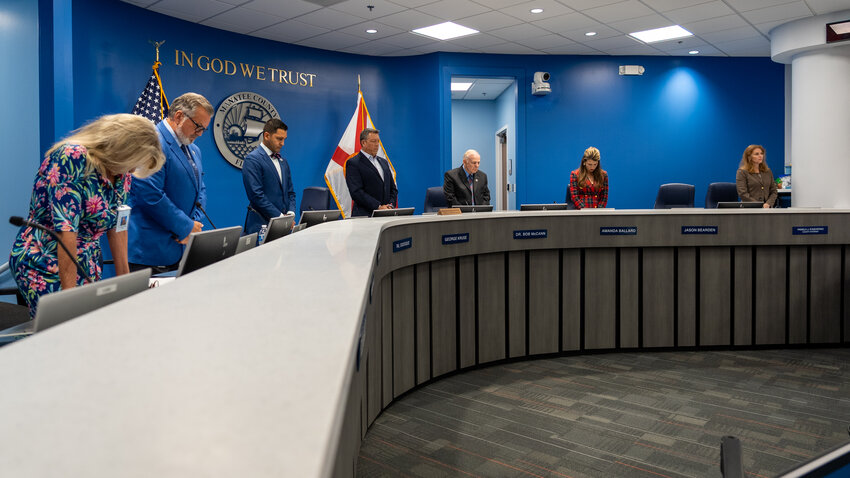 Manatee County Commissioners stand for invocation and pledge during a May 2025 board meeting in Honorable Patricia M. Glass Chambers