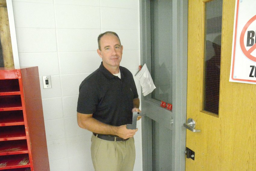 Jason Pursley takes a Z-Lock off the wall and gets ready to insert it in a lock on a door of a Skyline Elementary School classroom. This process takes 20 seconds or less.