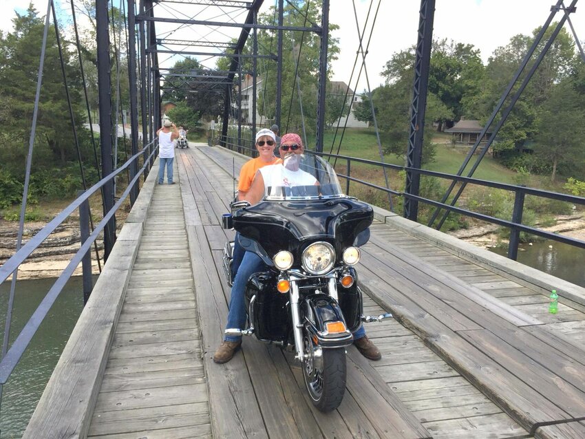 Russ and Amy Wisdom on their Harley-Davidson Ultra Classic crossing the wooden bridge at War Eagle, Arkansas.