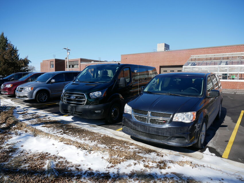 Without a current garage, the school vans are parked in the lot behind the high school building.