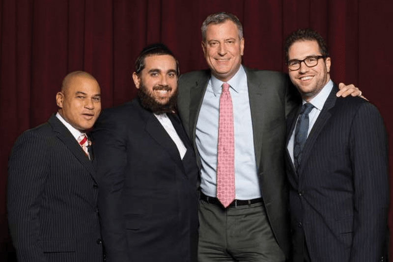 THEY AREN’T SMILING NOW: What Jona Rechnitz (right) described as a close relationship in which he and business partner Jeremy Reichberg (second from left) made large contributions to Mayor de Blasio and his political causes in return for access and special treatment from City Hall has been ruptured by criminal indictments of the two businessmen for schemes including alleged favor-trading with top police commanders. Mr. Rechnitz is appearing as a key prosecution witness against Mr. Reichberg and ex-Deputy Insp. James Grant, while the Mayor has denied doing anything improper, saying he wished he never met the two businessmen.