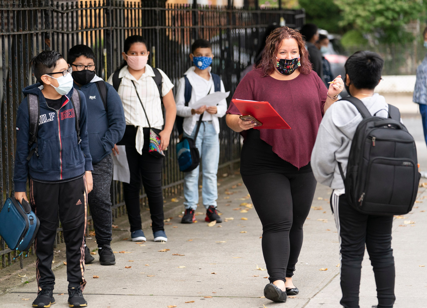 A teacher at PS 179 in Brooklyn greets students returning to school for blended-learning in September 2020. The 82 Department of Education staffers accused of submitting phony Covid vaccination cards will be placed back on payroll this fall.