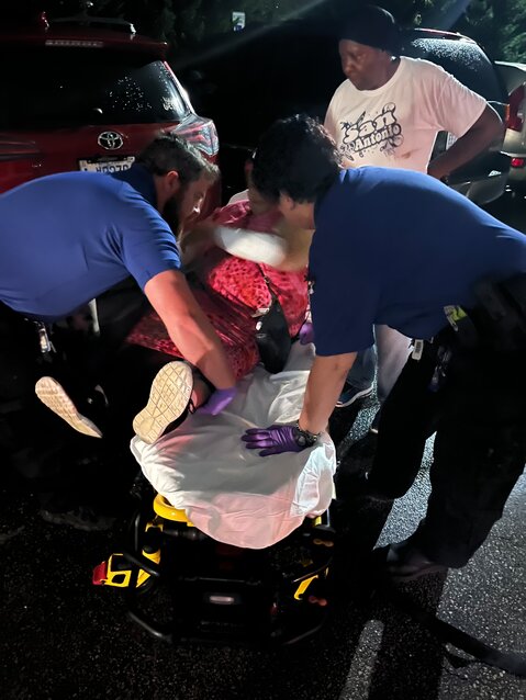 An elderly woman receiving medical attention after being attacked in the parking lot of Azalea Manor.