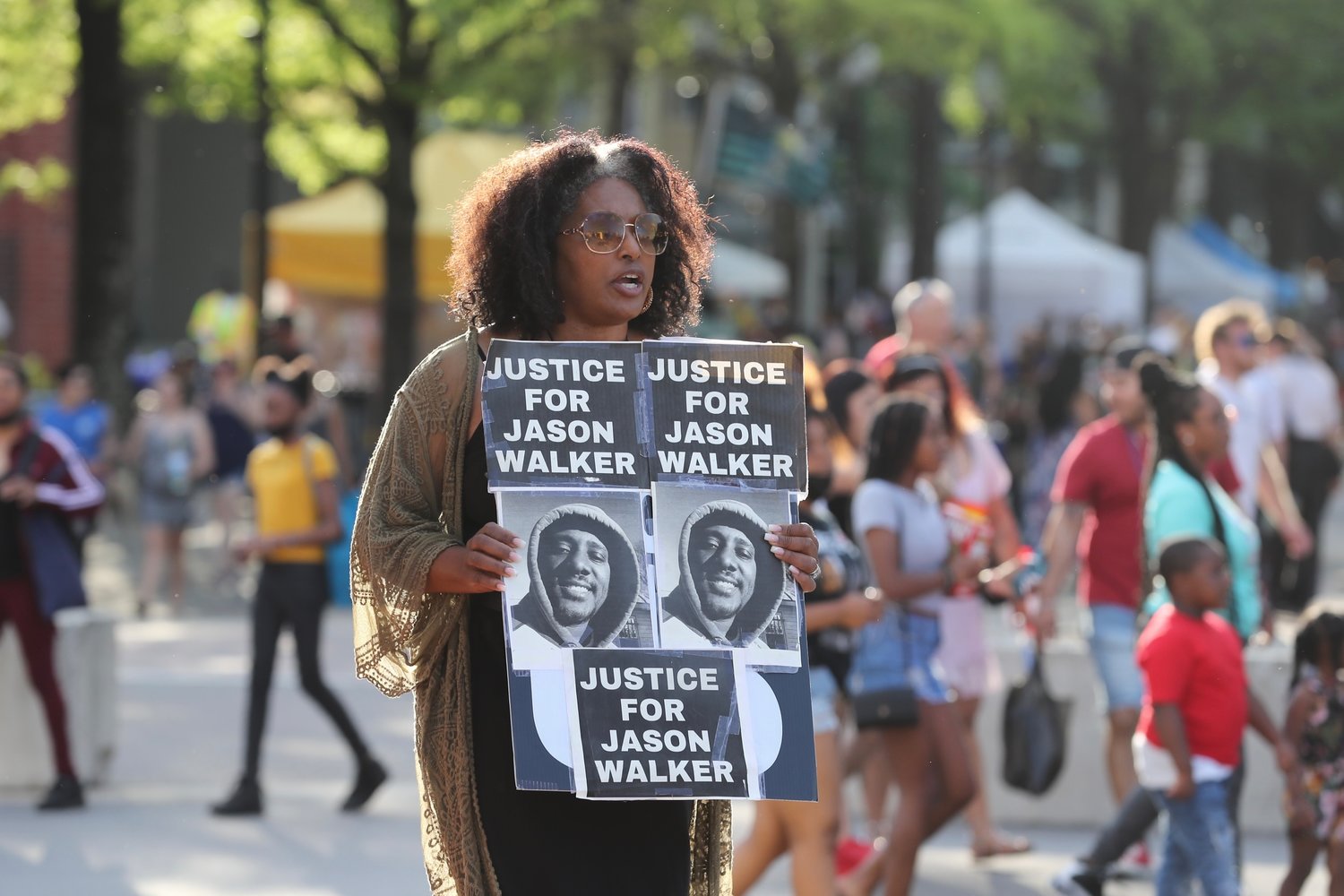 Protesters gathered at the Market House on Saturday to demonstrate against a decision this week by a special prosecutor not to charge a deputy in the shooting death of Jason Walker. Some people attending the Fayetteville Dogwood Festival stopped to watch the protesters.