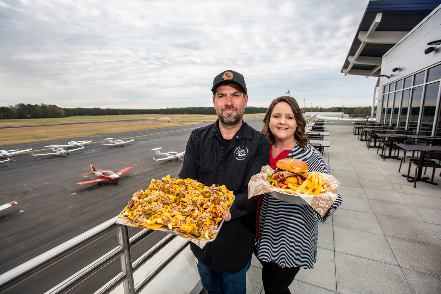 Philip and Monica Bailey holding barbecue loaded nachos and the meat master burger.