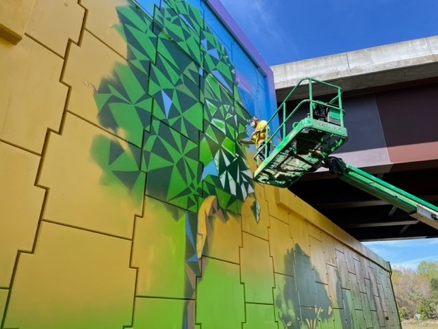 Artist Jermaine Powell puts the finishing touches on a mural at the intersection of Ramsey Street and Interstate 295. The first mural was completed Friday. Powell will now turn his attention to a second mural, which he hopes to have completed in four to six weeks