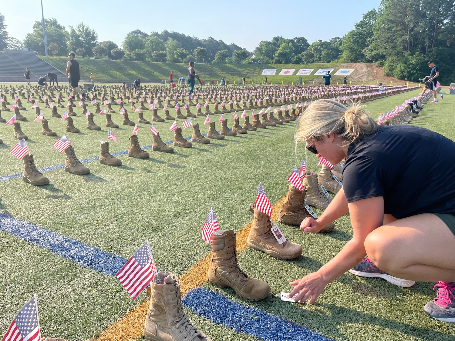 Anna Waggoner helps set up boots that are part of a memorial to fallen service members on display at Hedrick Stadium on Fort Bragg until Monday.