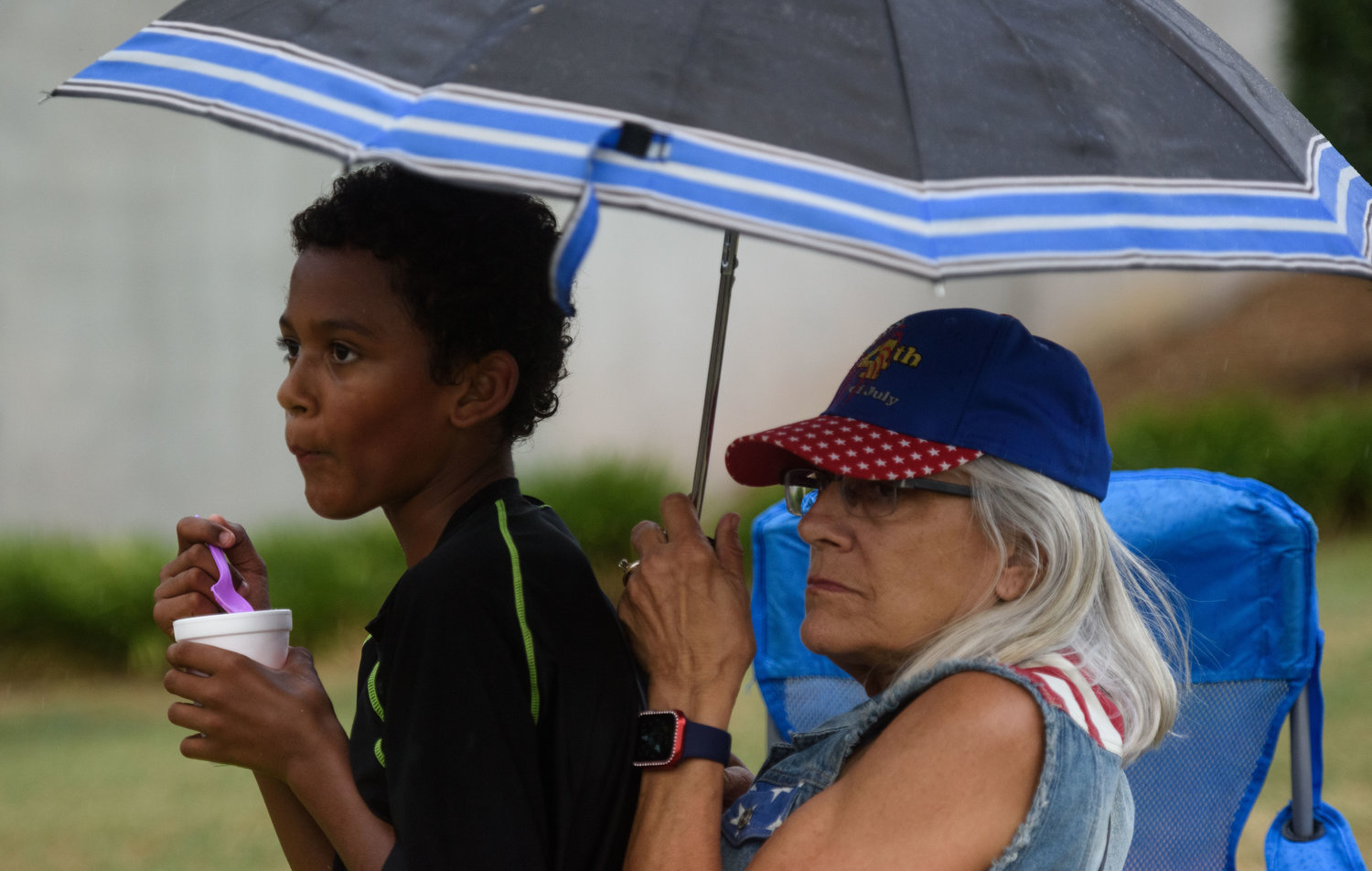 Vincent McKeithan, 10, is shielded from the rain by his grandmother Helena Hall.