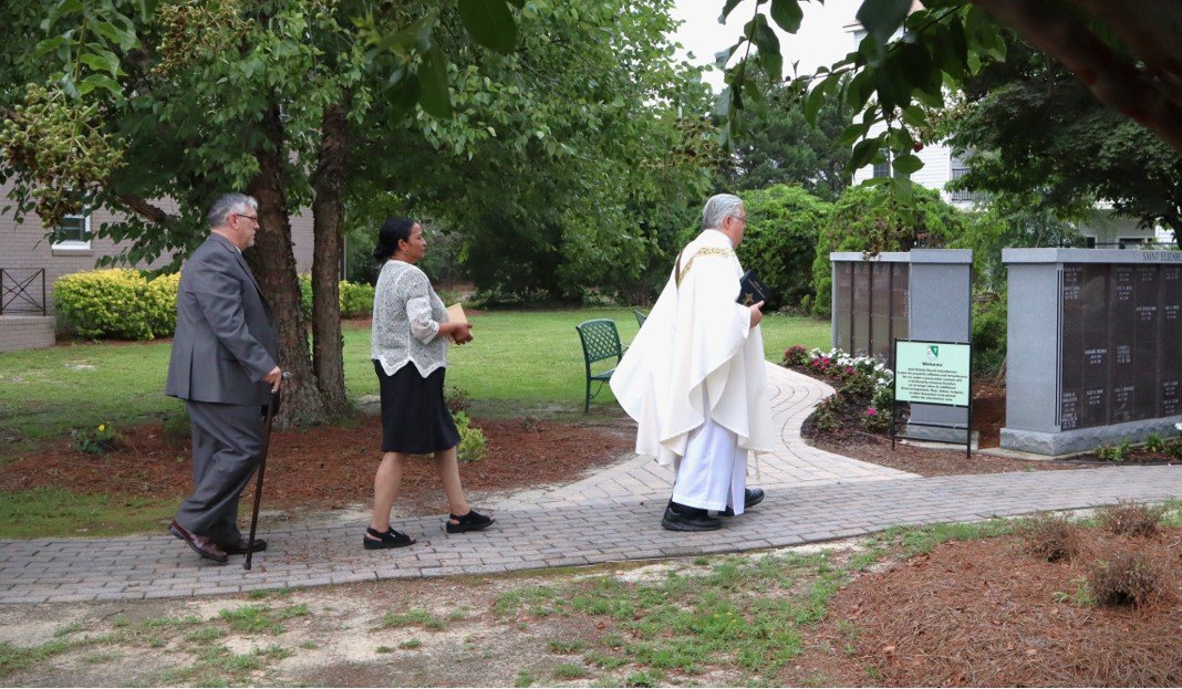 Father Gregory Lowchy leads the funeral processional to St. Patrick Catholic Church’s columbarium, where the remains of Jada Johnson will be laid to rest. Behind Lowchy are Johnson's grandmother Maria Iwanski and her grandfather Rick Iwanski. Johnson was shot and killed by a Fayetteville police officer on July 1.