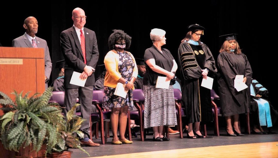 District leaders gather on stage during Cumberland County Schools' summer graduation Thursday at Jack Britt High School.