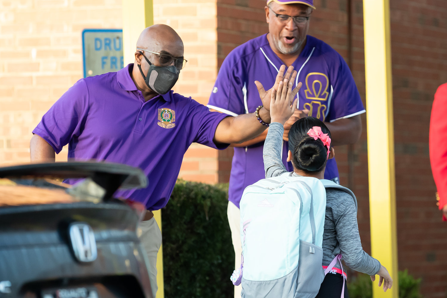 Members of the Omega Psi Phi Fraternity greet students as they arrive for the first day of school at Ferguson-Easley Elementary School on Monday.