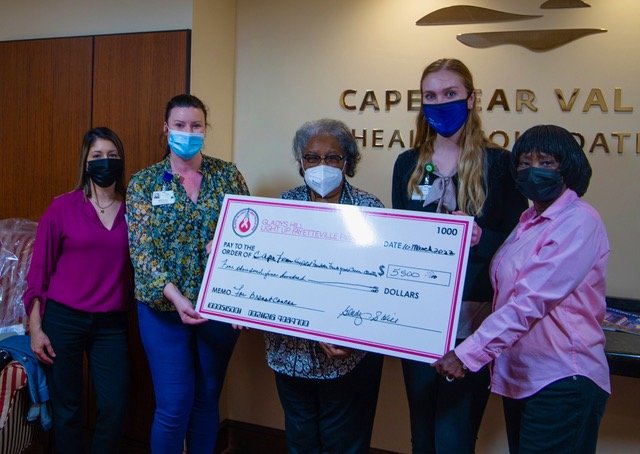 Gladys Hill, center, presents a check for $5,500 to Cape Fear Valley Health employees in March of 2022.