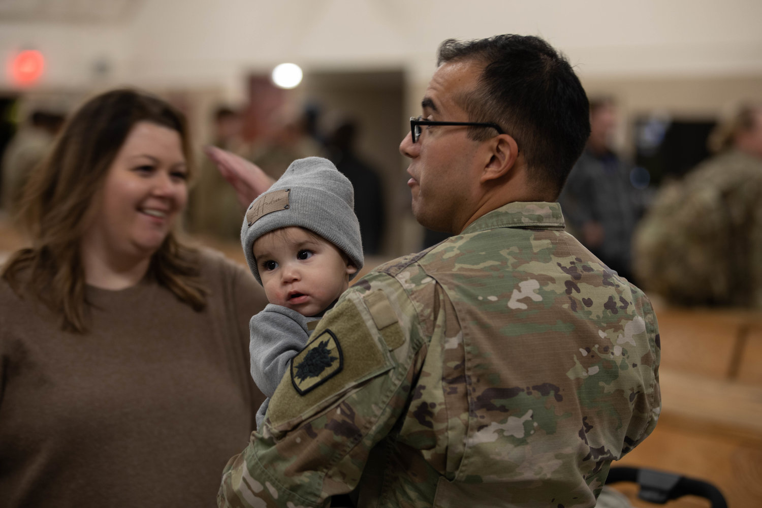 A soldier assigned to the 35th Corps Signal Brigade holds his baby as he is greeted by his family at Green Ramp on Friday. He was among the troops who returned home from a nine-month deployment to Europe.