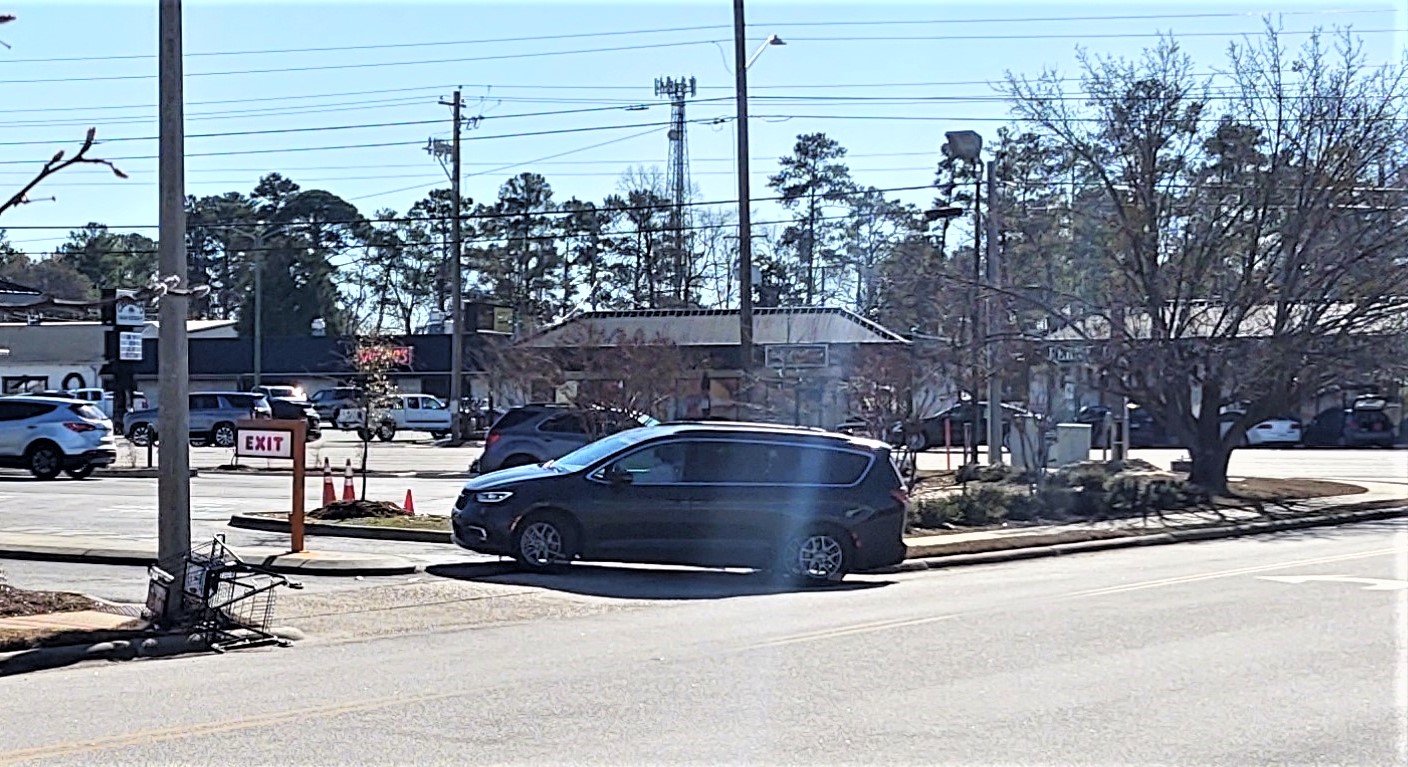 A shopping cart lies at the curb of Executive Place as a driver pulls into Dunkin at the intersection with Raeford Road.