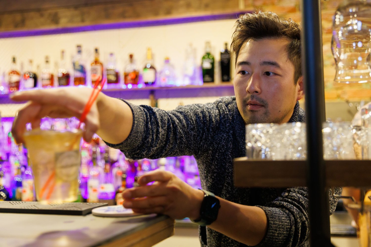 Josh Choi, the owner of Winterbloom downtown, prepares a drink in a cup designed for use in the 'social district,' where patrons can leave the premises of the bar where they bought a drink and wander within district limits.
