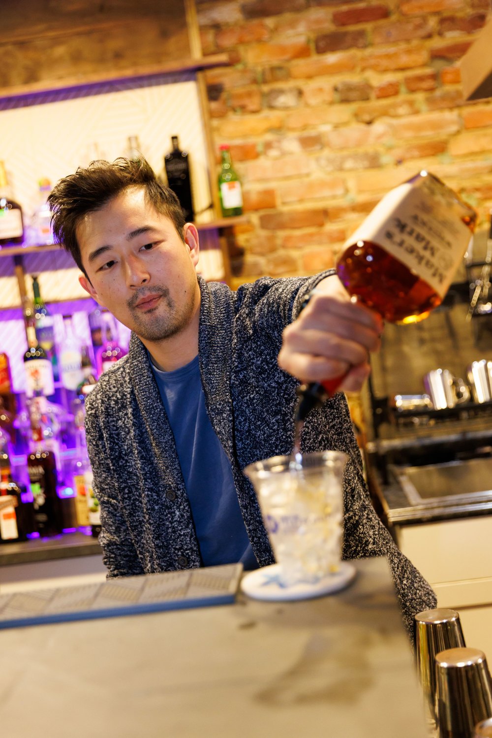 Josh Choi, the owner of Winterbloom, pours a drink in a cup used to serve patrons in the downtown social district.