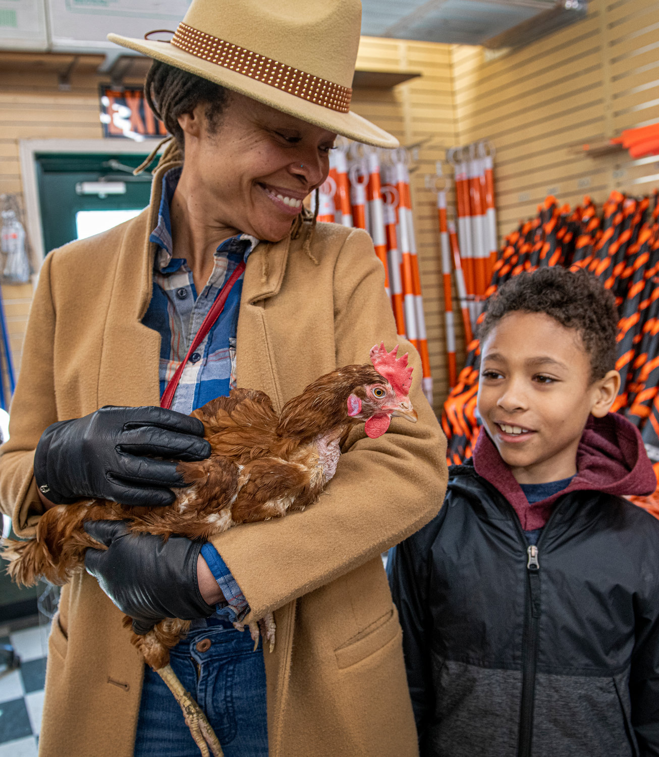 Sassy Womble holds a chicken while her son Elisha Womble, 9, looks on. The Wombles attended the free how-to seminar on backyard chickens held at Bell’s Seed Store.