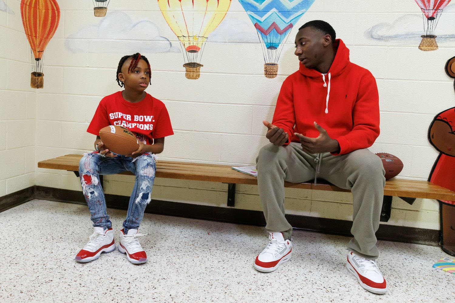 Joshua Williams, a star cornerback with the Super Bowl champion Kansas City Chiefs, chats with super fan Justin Malloy outside the main office of Loyd Auman Elementary School on Thursday.
