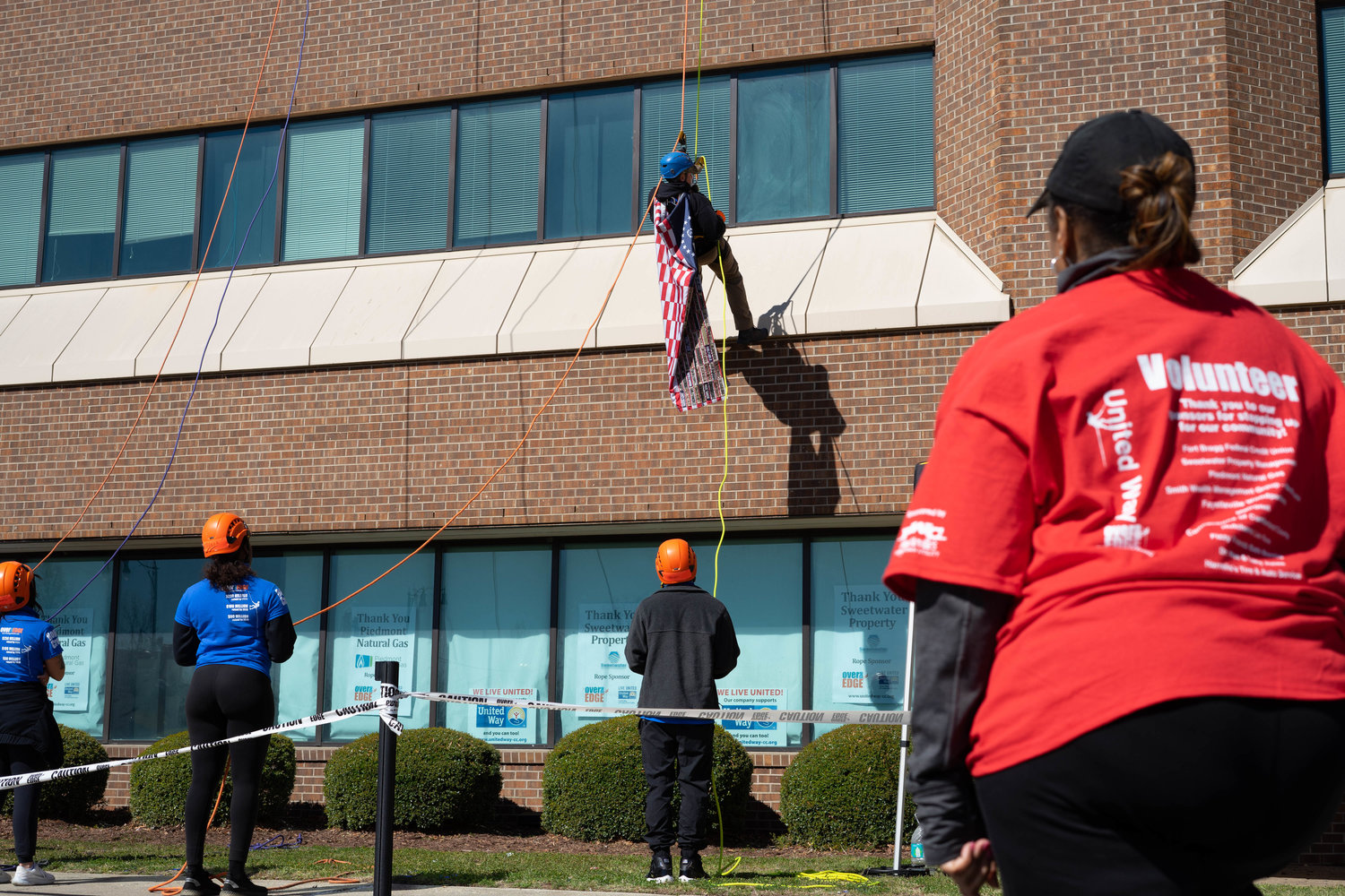 Observers watch as someone crawls down the building at United Way's Over the Edge fundraiser.