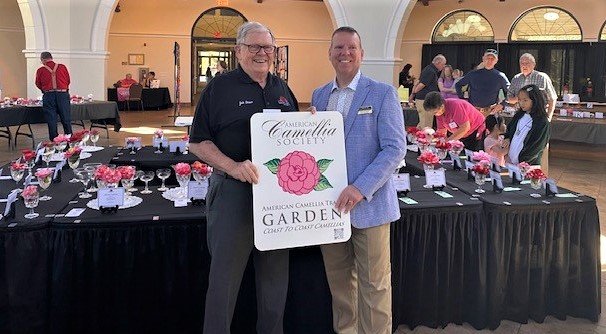 Jack Dewar, co-chair of the Fayetteville Camellia Show & Plant Sale, presents the American Camellia Society's recognition of Cape Fear Botanical Garden as part of the American Camellia Trail to Botanical Garden CEO Chris Hoffman.