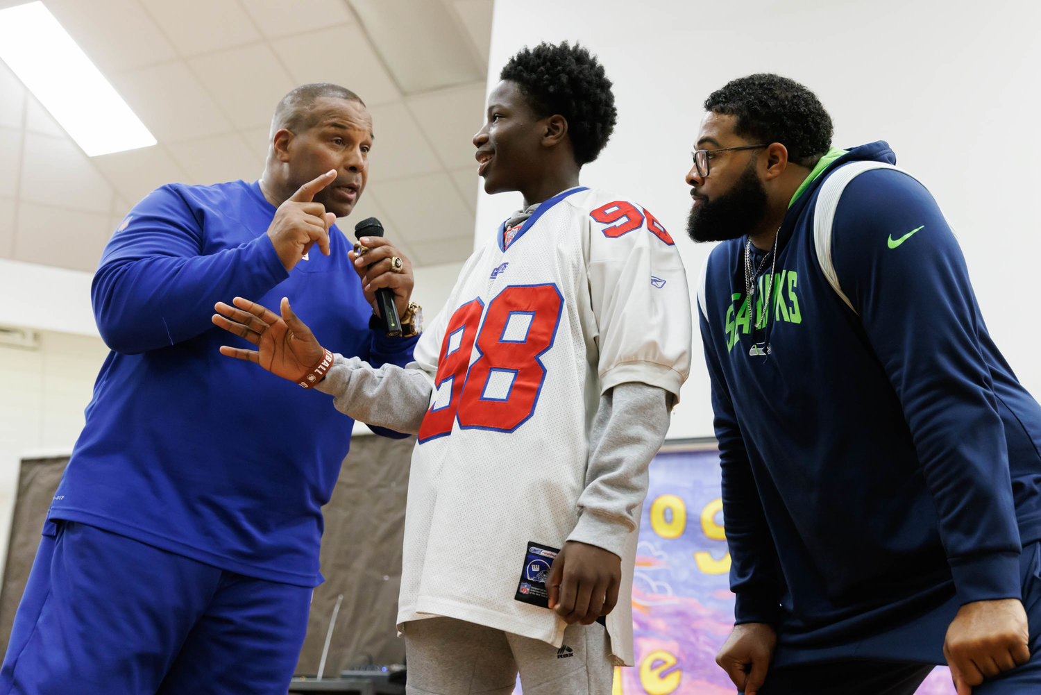 Former NFL player Keith Davis and college great Germard Reed, right, get help from a student at Luther "Nick" Jeralds Middle School.