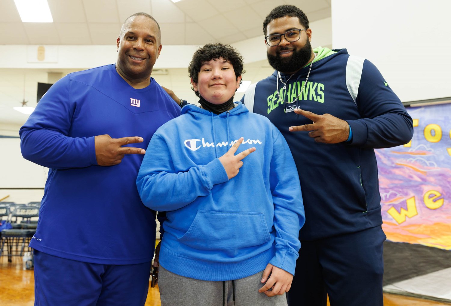 Keith Davis and Germard Reed flash the victory sign with a student at Luther "Nick" Jeralds Middle School.