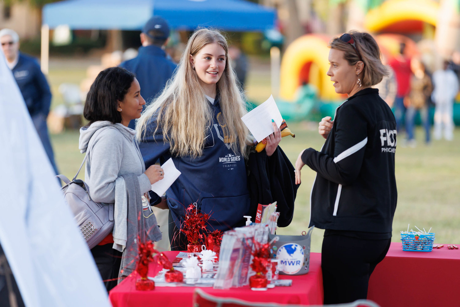 Rosa Creel (L) and Emma Young speak with Anna Miller of the Pivot Physical Therapy booth during the All American Race on Fort Bragg on March 25, 2023.  Tony Wooten/CityView Media