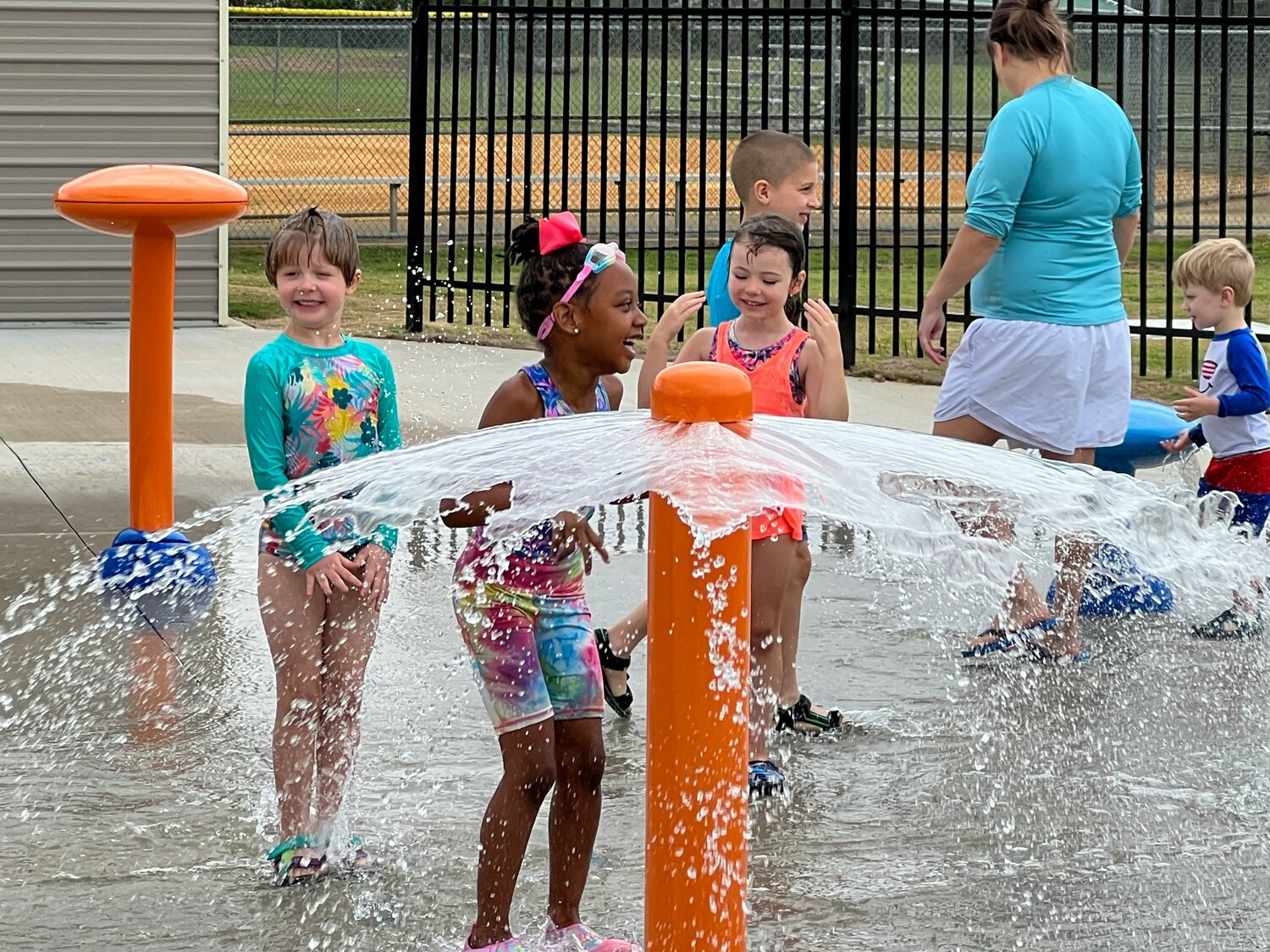 Children play on one of the city's splash pads, which have opened for the season.