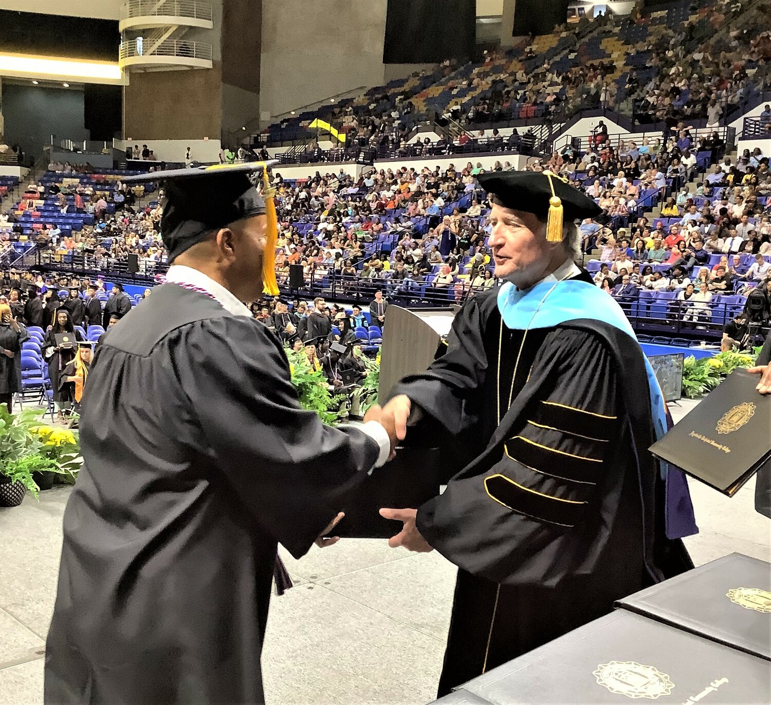 Fayetteville Technical Community College President Mark Sorrells congratulates a graduation during commencement Friday at the Crown Coliseum.