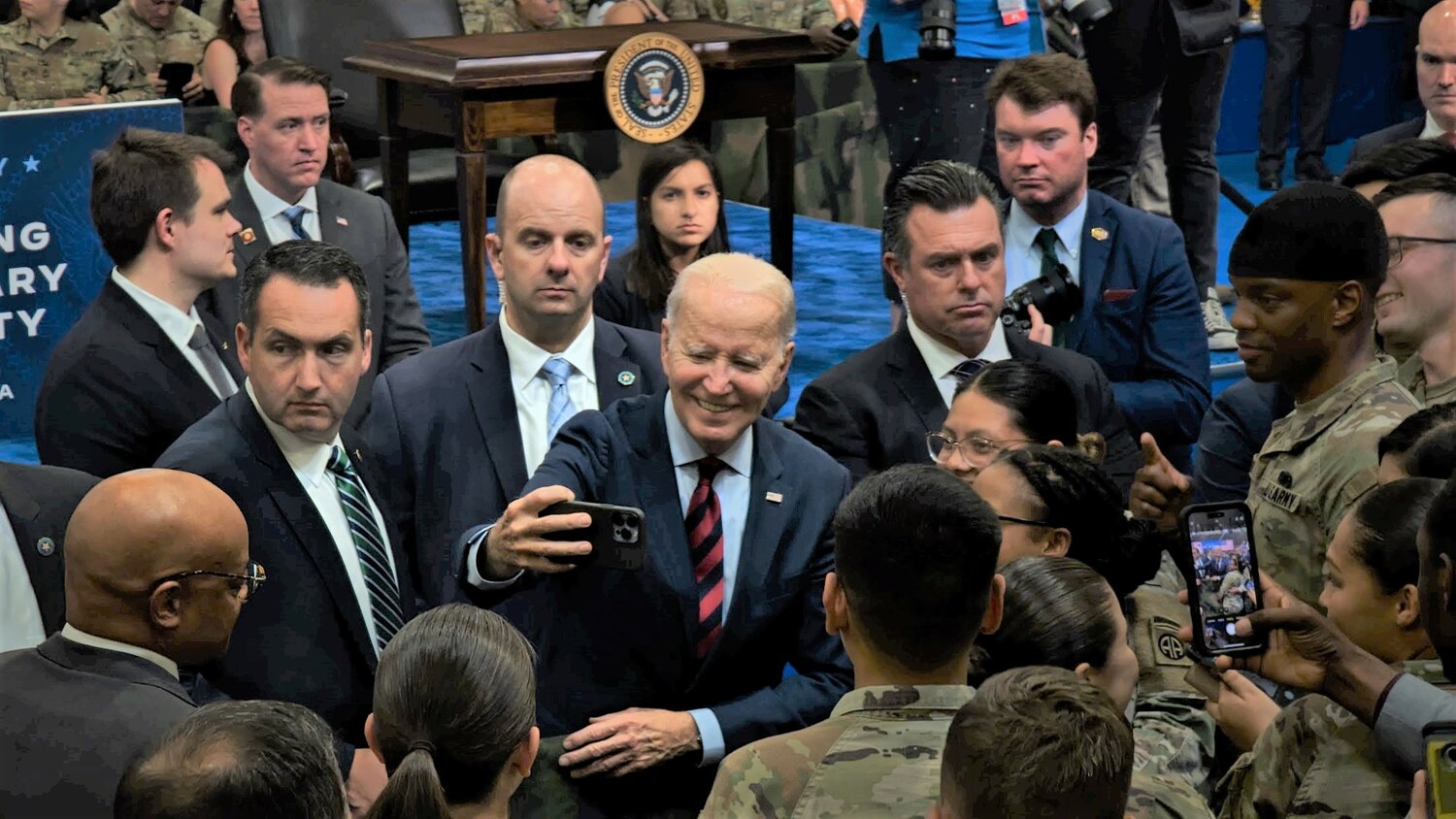 President Joe Biden, following his speech concerning the executive order on military family support, takes selfies with military personnel on Friday at Fort Liberty.