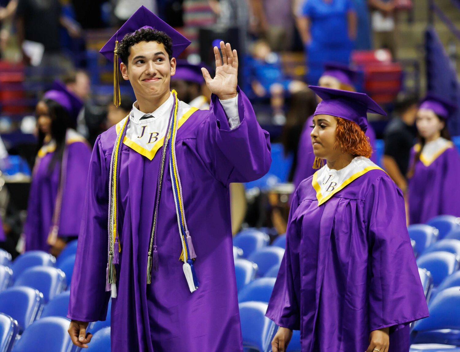 A Jack Britt High School student waves to someone in the crowd during the 2023 commencement Wednesday at the Crown Coliseum.