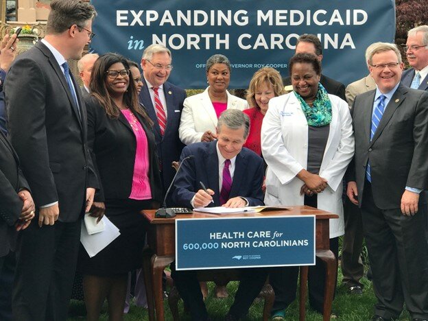 Gov. Roy Cooper signs House Bill 76 into law. He is surrounded by, from left, N.C. Health and Human Services Secretary Kody Kinsley; Little Believers Academy owner Cassandra Brooks; advocate Nicole Dozier; state Sen. Jim Burgin, R-Angier; Rep. Carla Cunningham, D-Charlotte; Sen. Joyce Krawiec, R-Kernersville; Dr. Eleanor Greene; state Sen. Kevin Corbin, R-Franklin; House Speaker Tim Moore, R-Kings Mountain; and Rep. Donny Lambeth, R-Winston-Salem.