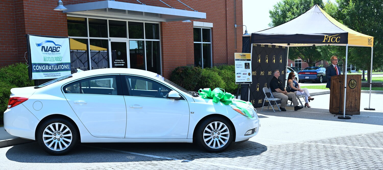 With the 2011 white Buick Regal in the foreground at FTCC’s Collision U, FTCC President Mark Sorrells discusses the Recycled Rides program.