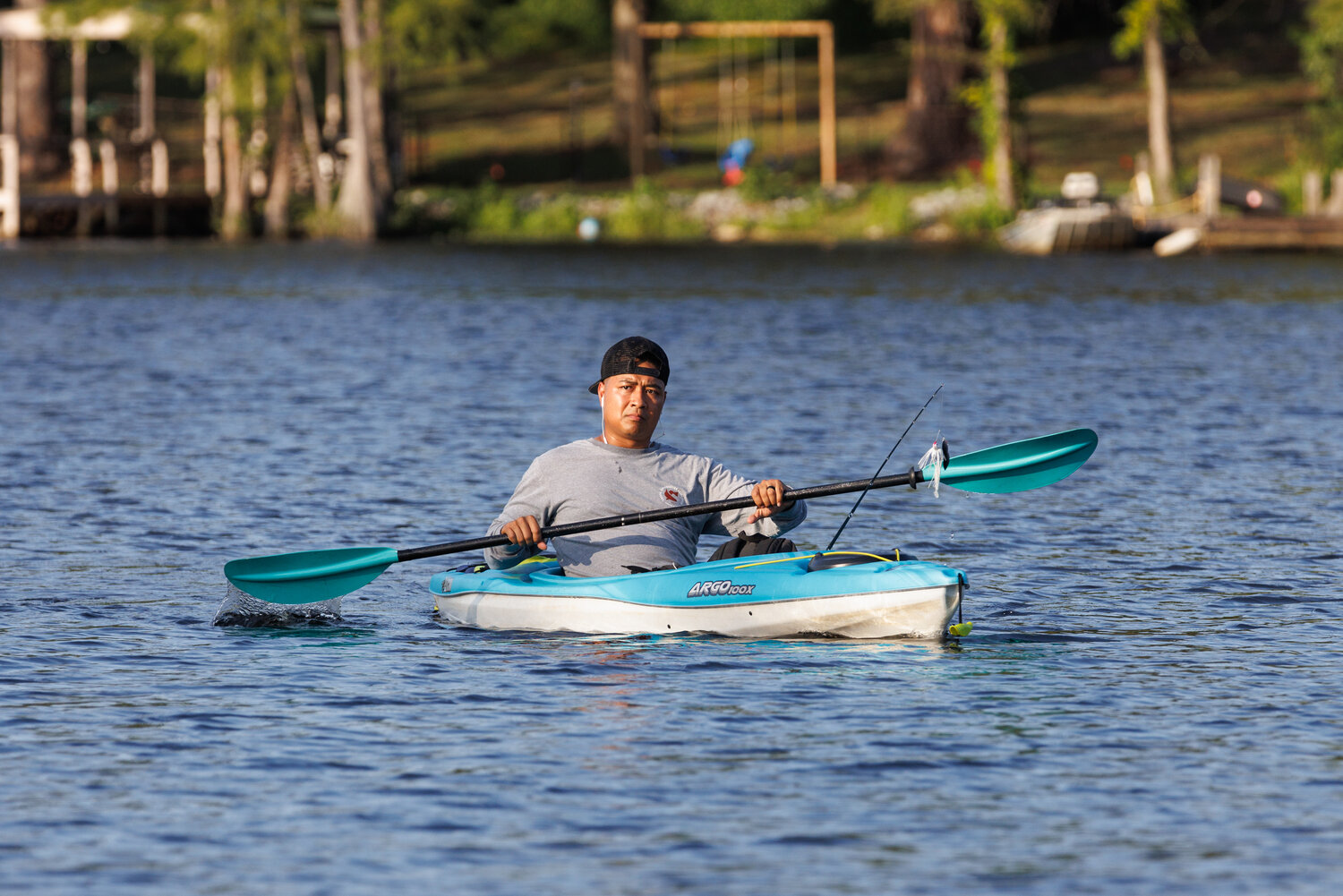 Tommy Souimaniphanh, a soldier at Fort Liberty, casually guides his kayak in following a day on Hope Mills Lake.