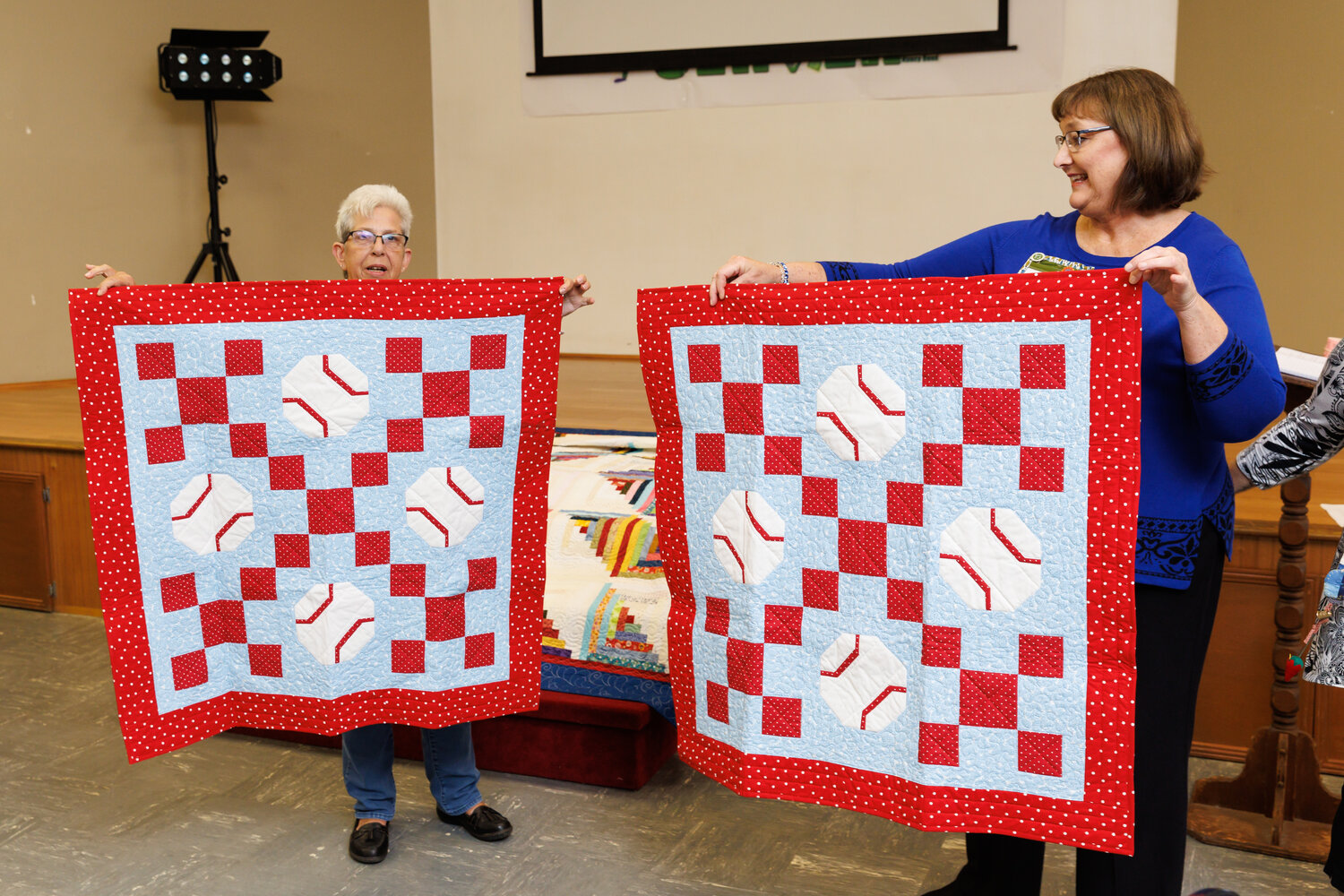 Debby Grice (right) assists Sona Molder in displaying a dual set of quilts she made for the NICU. Photo: Tony Wooten