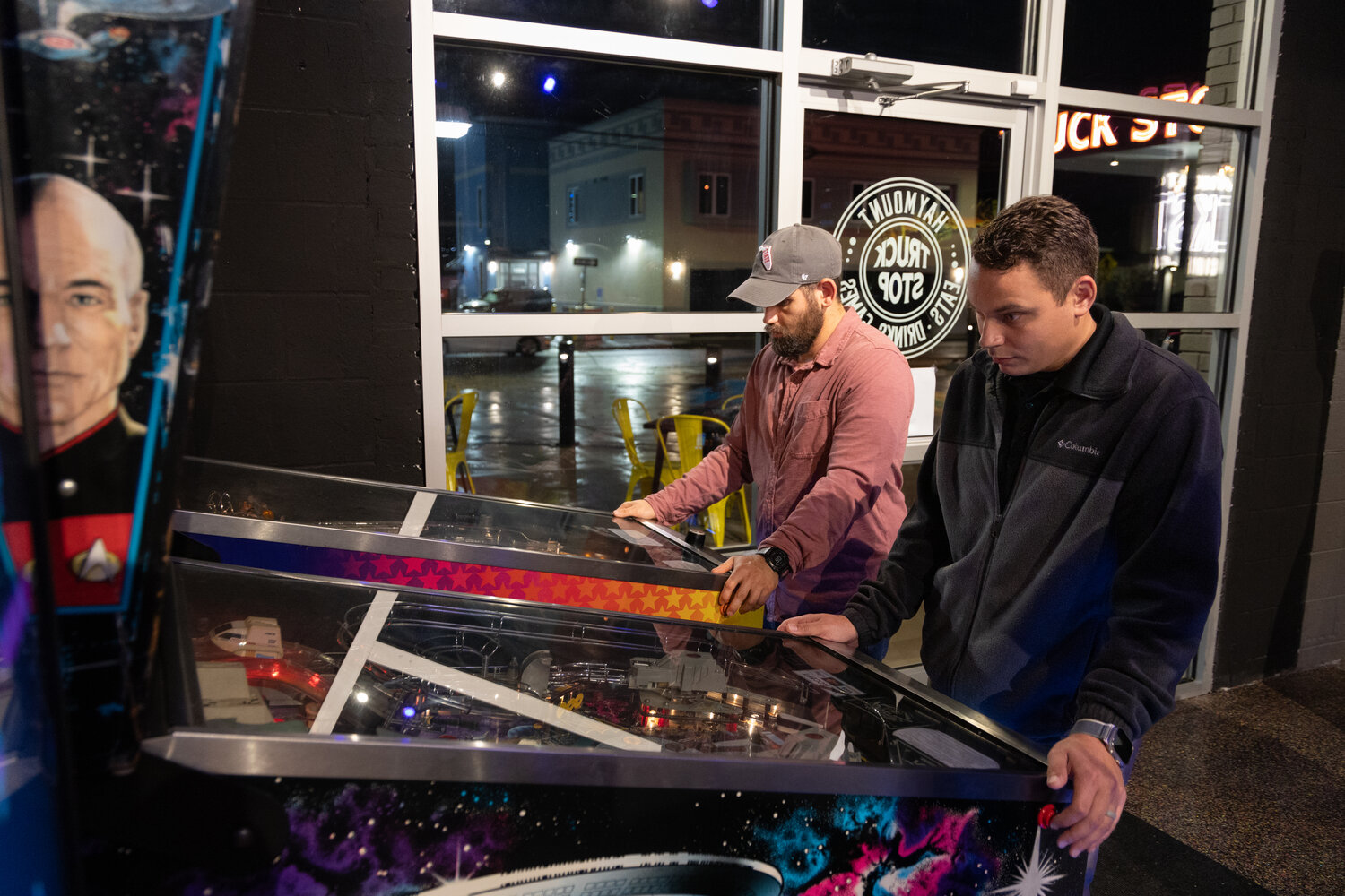 Jordan Finlayson, in the hat, and Shane Caulder play pinball at the soft opening of the Haymount Truck Stop.