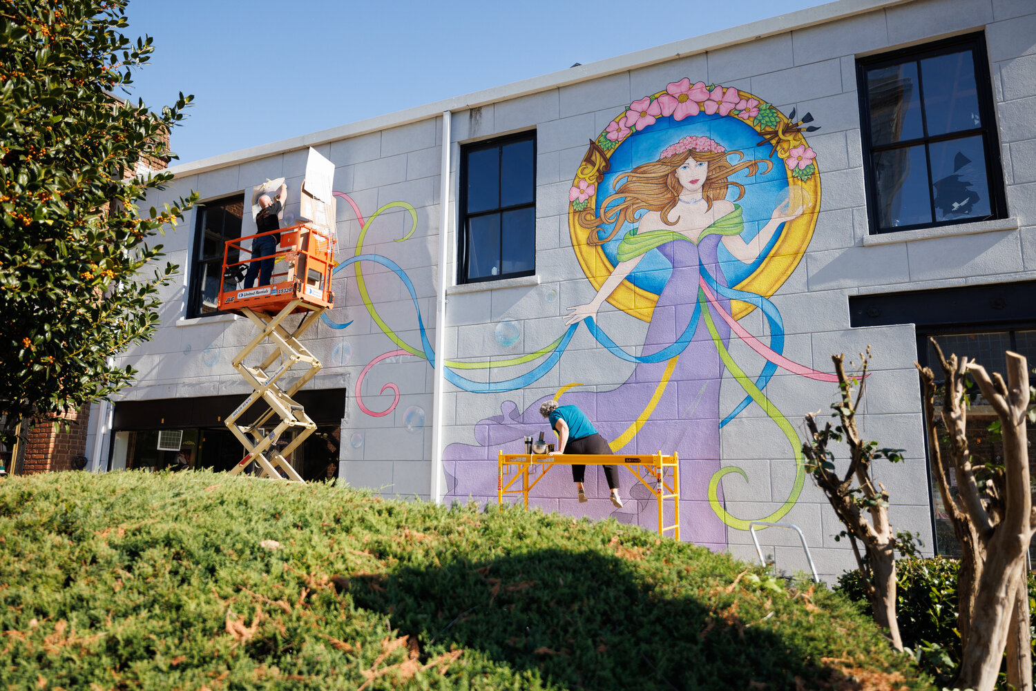 The "Lady Muriel" mural adorns the western side of the 101 Person St. building, which houses The Sweet Palette and Blanc Coffee Roasters, facing the intersection of Market Square. “I looked up what Muriel meant, and it meant ‘sparkling and bright,’” Patsy said. “And I thought that was perfect because [the mural] is brightening up this corner on Market Street.”